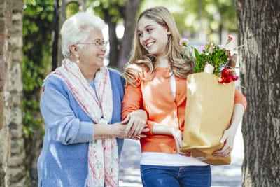 Older adult woman walking home from the grocery store with her granddaughter.